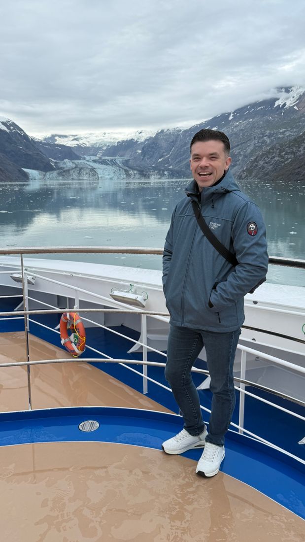 Justin laughing on a ship deck in front of a glacier in Alaska